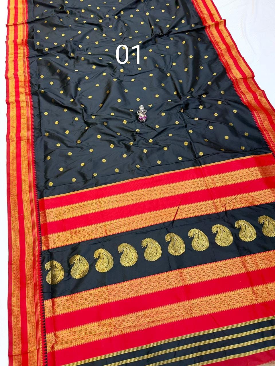 Black saree with golden zari work and red borders.