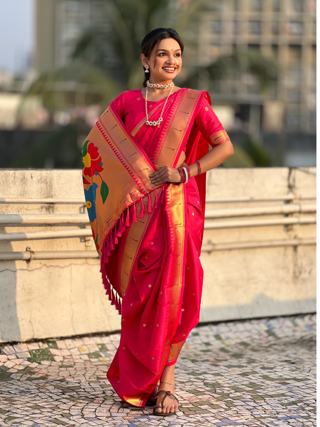 A woman wearing a vibrant pink Nauvari saree with a decorative border.