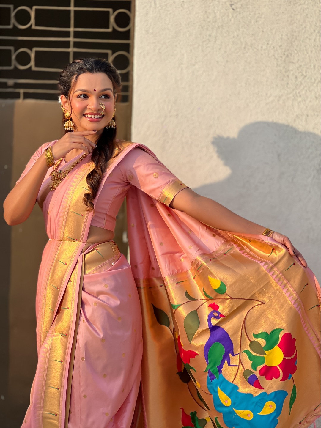 A woman wearing a pink Nauvari saree with floral designs.