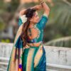 A woman wearing a teal Nauvari saree with floral embroidery.