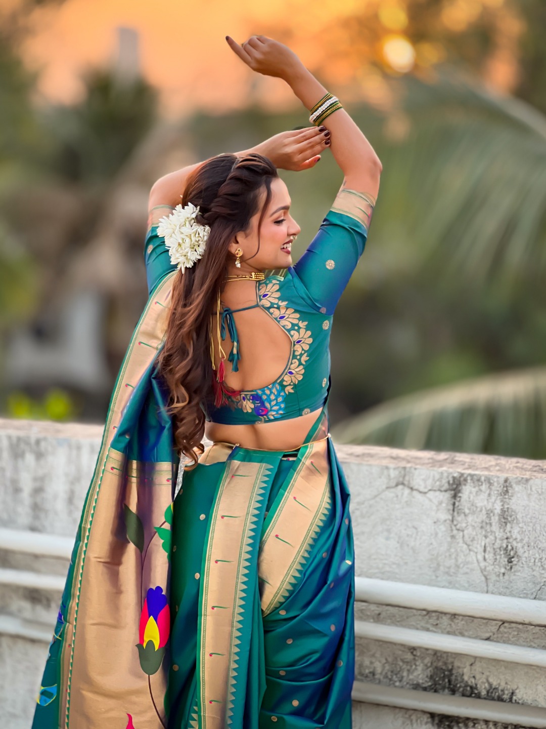 A woman wearing a teal Nauvari saree with floral embroidery.