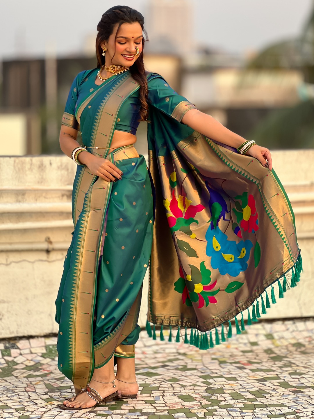 A woman elegantly draped in a teal Nauvari saree with floral designs.
