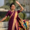 A woman wearing a purple Nauvari saree with floral designs.