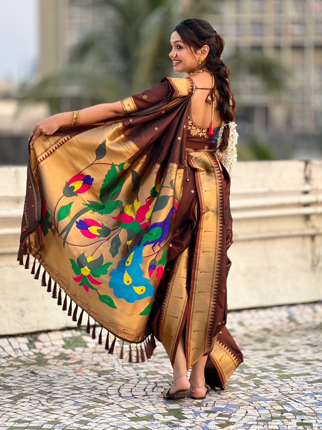A woman draped in a Nauvari saree with floral patterns.