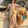 A woman elegantly draped in a beige Nauvari saree with floral designs.