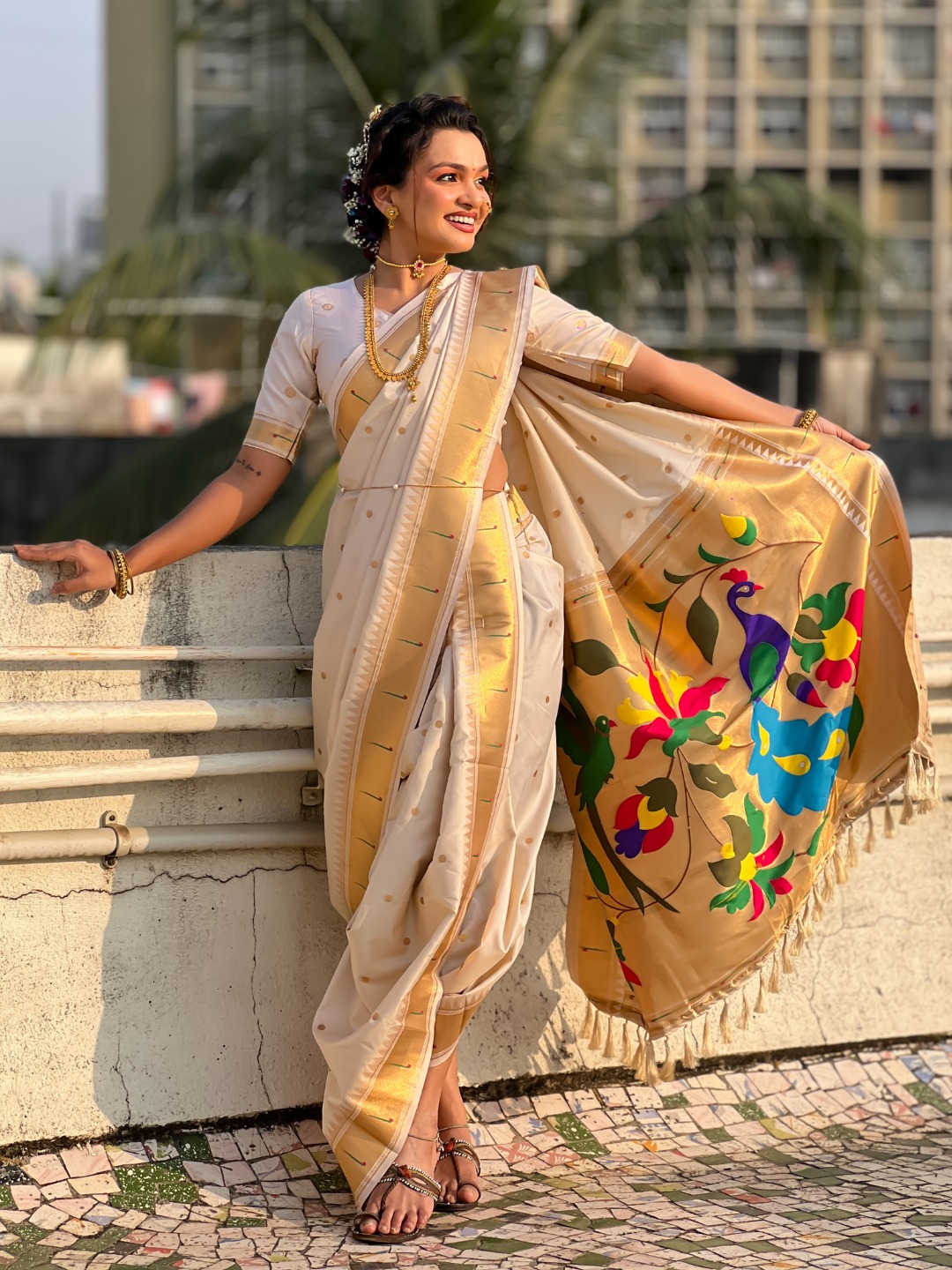 A woman elegantly draped in a beige Nauvari saree with floral designs.